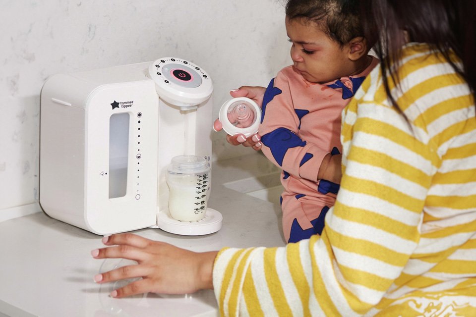 A mother using a Tommee Tippee Perfect Preparation filter to fill her baby's bottle.